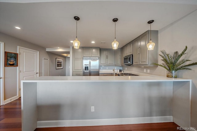 kitchen with kitchen peninsula, appliances with stainless steel finishes, dark hardwood / wood-style floors, and gray cabinetry