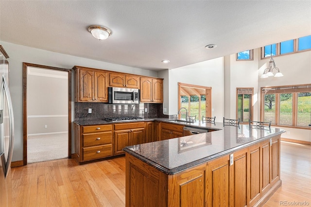 kitchen with tasteful backsplash, dark stone countertops, a chandelier, and stainless steel appliances