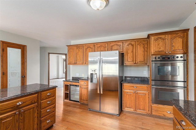 kitchen with dark stone counters, light hardwood / wood-style floors, and appliances with stainless steel finishes