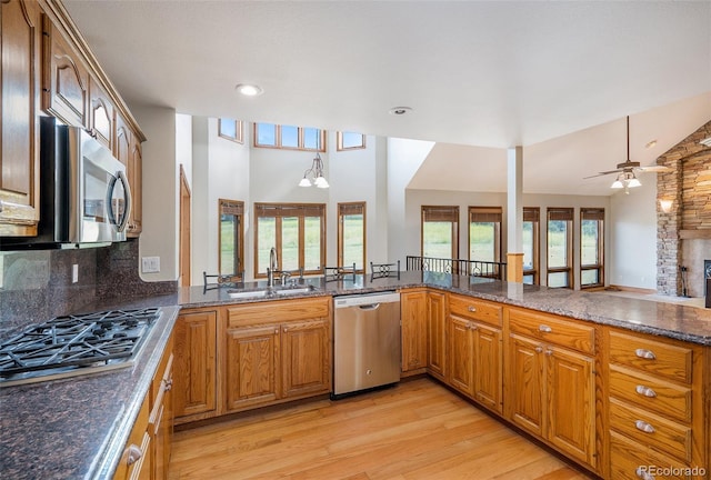 kitchen with sink, light hardwood / wood-style flooring, decorative backsplash, ceiling fan, and appliances with stainless steel finishes