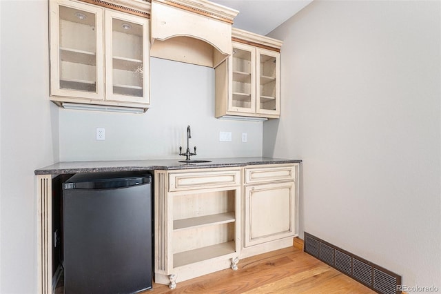 bar featuring cream cabinets, refrigerator, light hardwood / wood-style flooring, and sink