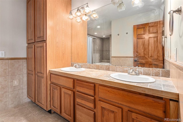 bathroom with a shower, vanity, tile patterned floors, and tile walls