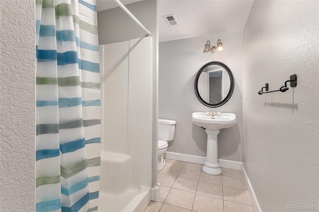 bathroom featuring tile patterned flooring, toilet, and curtained shower