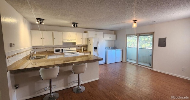 kitchen with washer and dryer, sink, white cabinets, kitchen peninsula, and white appliances