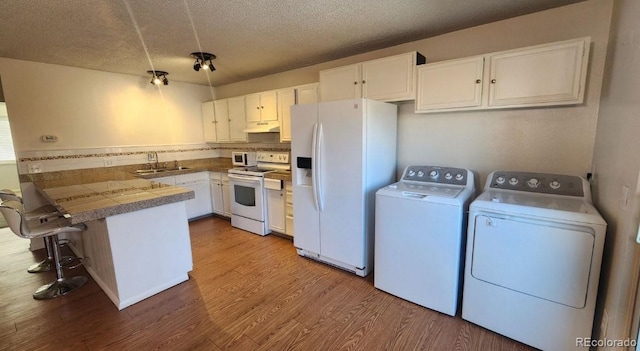 kitchen featuring sink, white appliances, kitchen peninsula, and white cabinets