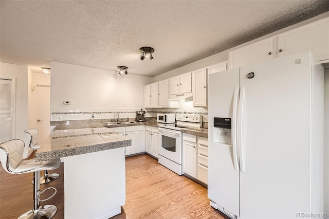 kitchen with white appliances, kitchen peninsula, and white cabinets