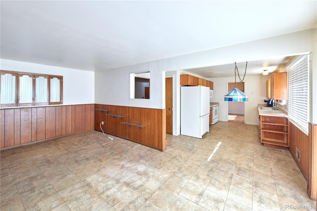 6579 S Lincoln St, Centennial, CO 80121 - kitchen featuring white appliances, wood walls, a wainscoted wall, brown cabinetry, and light countertops
