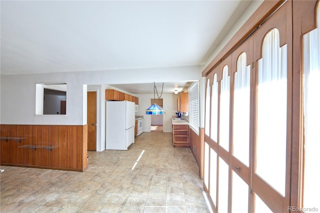 6579 S Lincoln St, Centennial, CO 80121 - kitchen featuring white appliances, brown cabinets, a wainscoted wall, wooden walls, and light countertops