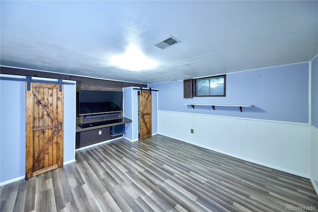 6579 S Lincoln St, Centennial, CO 80121 - unfurnished living room featuring a barn door, wood finished floors, a textured ceiling, and a wainscoted wall