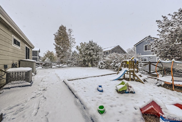 yard covered in snow featuring central air condition unit, fence, and a playground