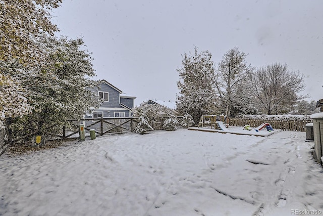 snowy yard featuring a playground and fence