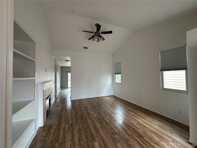 unfurnished living room with lofted ceiling, a fireplace, visible vents, a ceiling fan, and dark wood-style floors