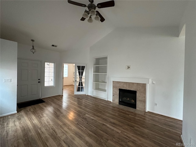 unfurnished living room featuring lofted ceiling, built in shelves, a fireplace, wood finished floors, and visible vents