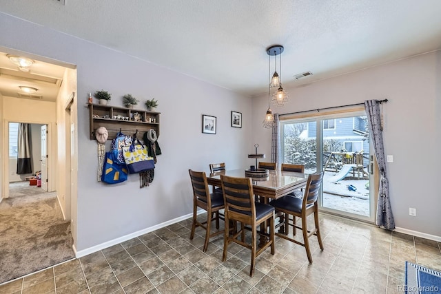 carpeted dining space with visible vents, a textured ceiling, and baseboards