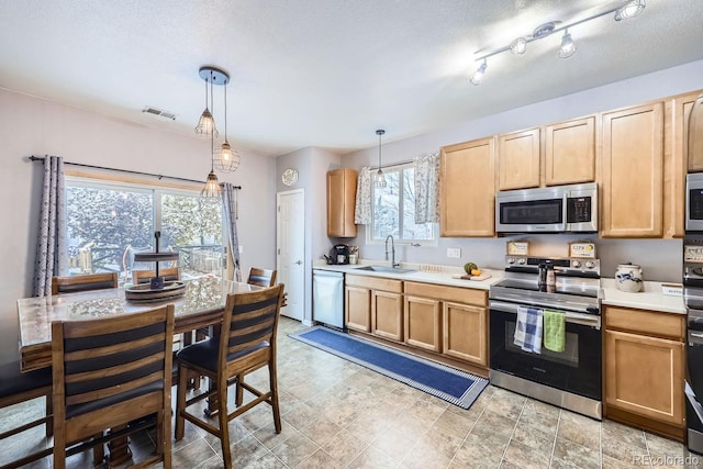 kitchen featuring a sink, visible vents, light countertops, appliances with stainless steel finishes, and pendant lighting