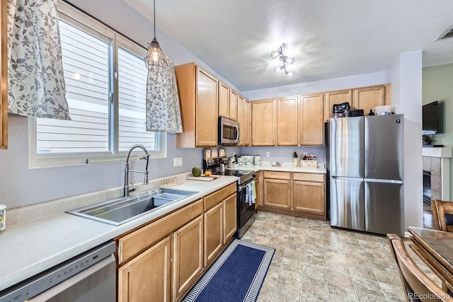 kitchen with pendant lighting, stainless steel appliances, light countertops, light brown cabinets, and a sink