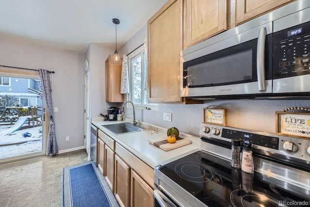 kitchen featuring baseboards, stainless steel appliances, light countertops, light brown cabinetry, and a sink