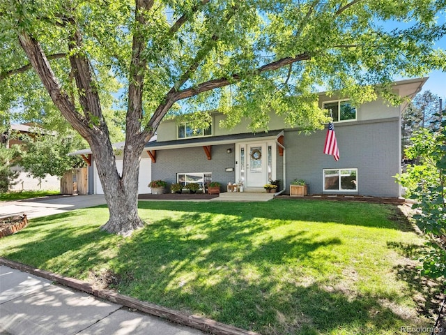 view of front of home featuring a garage, a front yard, concrete driveway, and brick siding