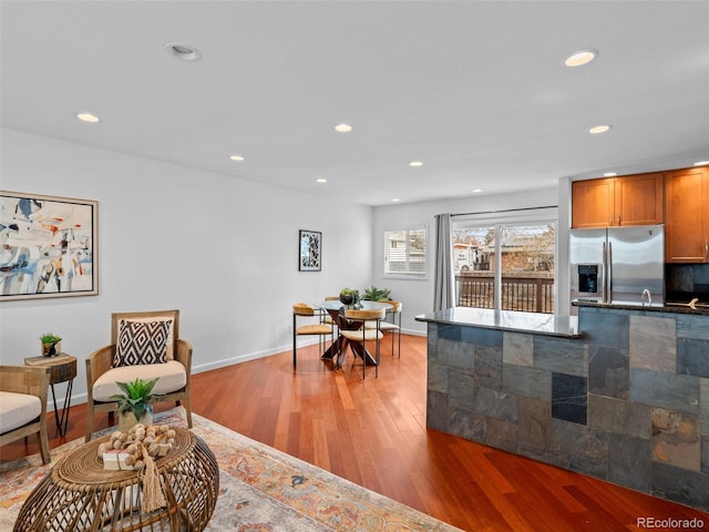 kitchen featuring recessed lighting, brown cabinets, light wood finished floors, dark countertops, and stainless steel fridge