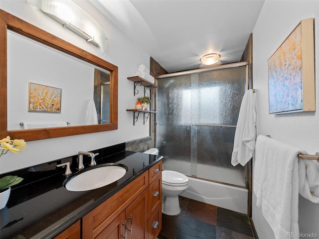 bathroom featuring toilet, bath / shower combo with glass door, and vanity