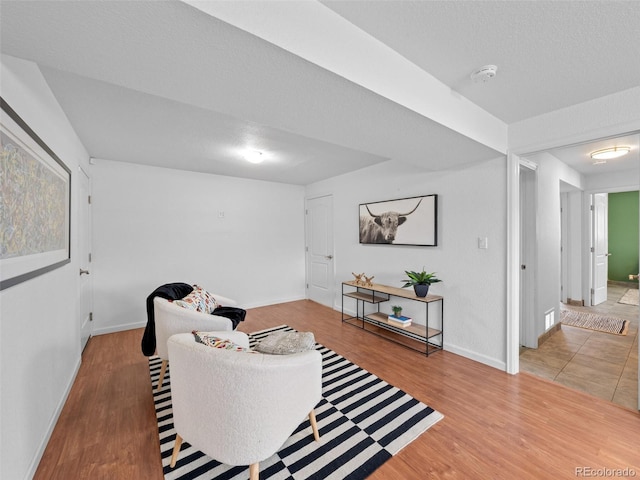 living area with a textured ceiling, baseboards, and wood finished floors