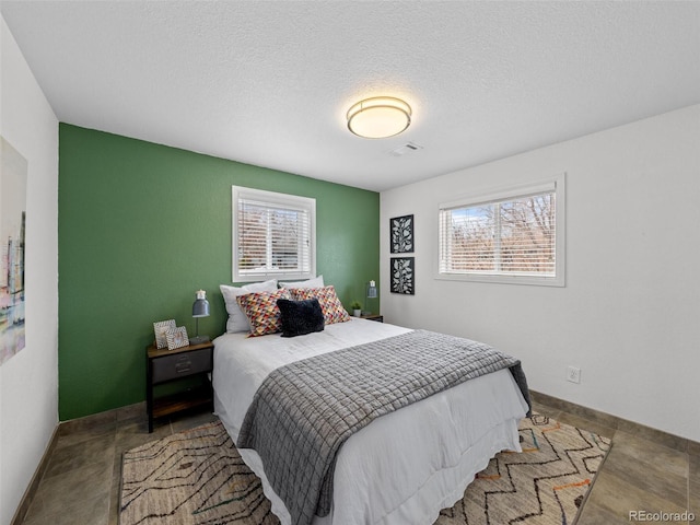 bedroom with visible vents, multiple windows, a textured ceiling, and baseboards