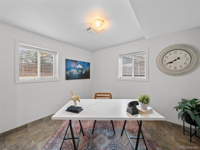 home office with a textured ceiling, a wealth of natural light, visible vents, and baseboards