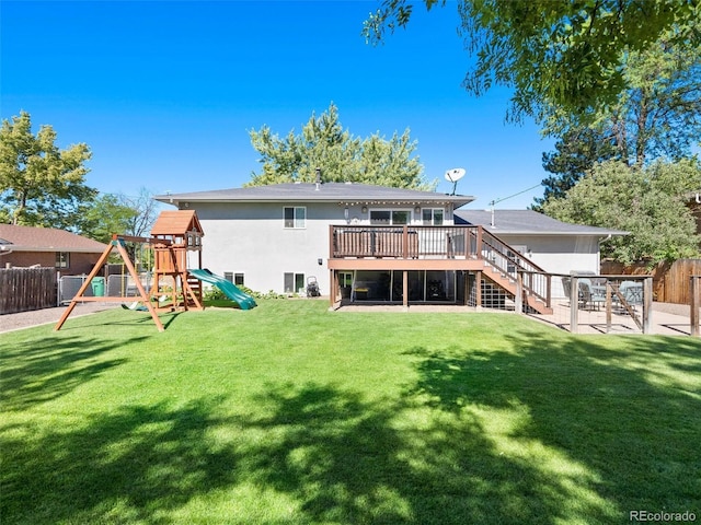 rear view of property featuring a playground, a fenced backyard, stairway, a lawn, and stucco siding