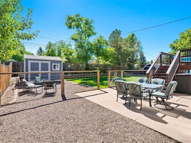 view of patio / terrace featuring outdoor dining area, a fenced backyard, an outdoor structure, stairs, and a storage unit