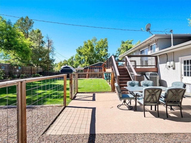 view of patio featuring outdoor dining area, a playground, fence, stairs, and a wooden deck