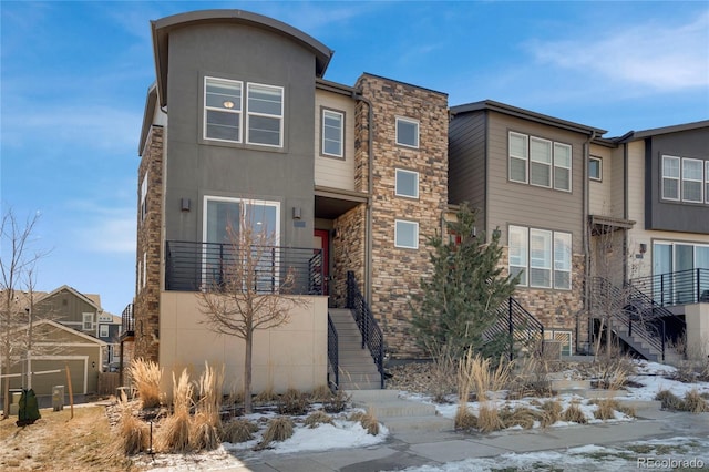 view of front of house with stone siding, stairs, and stucco siding