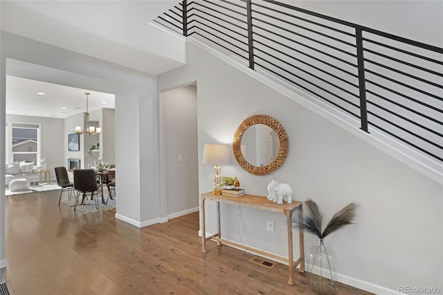 interior space with baseboards, visible vents, a chandelier, and wood finished floors