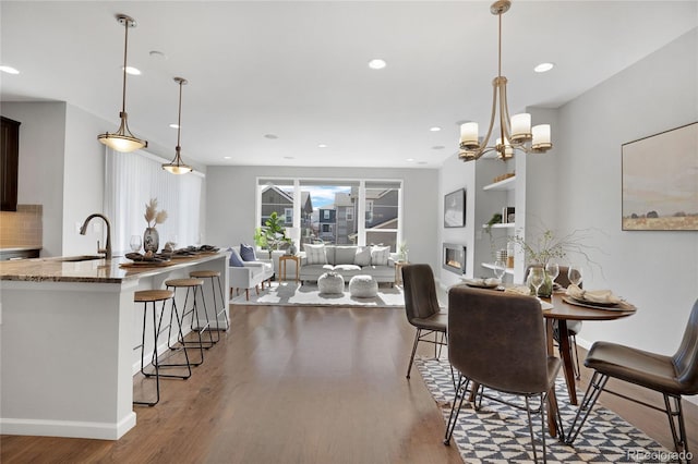 dining area featuring baseboards, a glass covered fireplace, wood finished floors, and recessed lighting