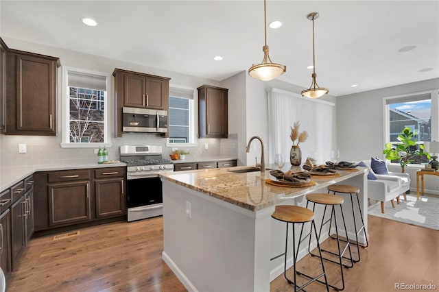 kitchen featuring stainless steel appliances, light wood-type flooring, a sink, and dark brown cabinetry