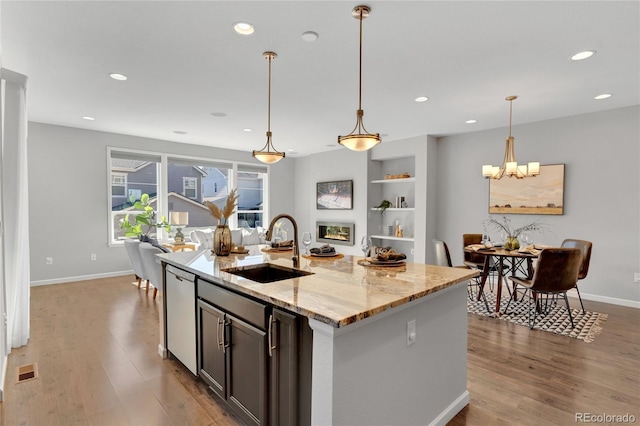 kitchen with light stone counters, wood finished floors, a sink, visible vents, and dishwasher