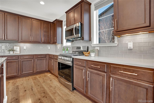 kitchen with recessed lighting, stainless steel appliances, light wood-style floors, light countertops, and decorative backsplash