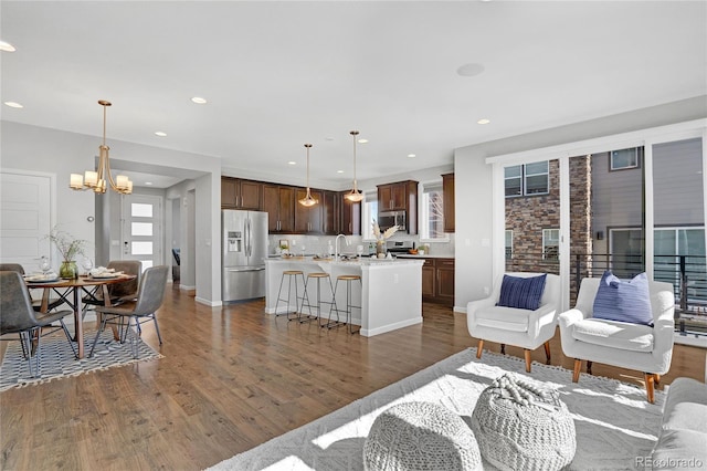 living area with dark wood-style floors, recessed lighting, baseboards, and a notable chandelier