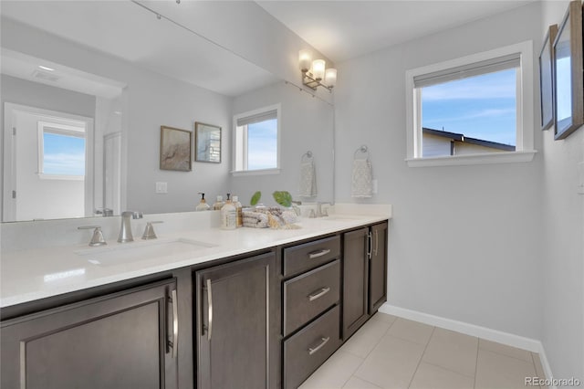 full bath with double vanity, tile patterned floors, a sink, and baseboards