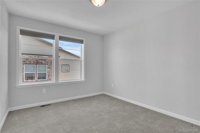 carpeted empty room featuring baseboards and visible vents