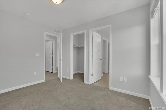 unfurnished bedroom with visible vents, baseboards, carpet, a spacious closet, and a closet