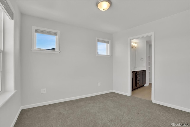 unfurnished bedroom featuring carpet flooring, connected bathroom, and baseboards