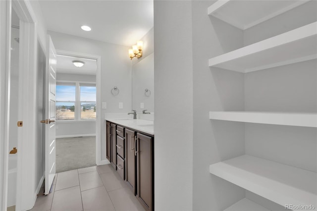 full bath with double vanity, baseboards, a sink, and tile patterned floors