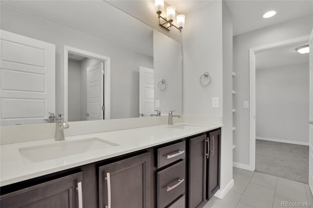 bathroom with double vanity, tile patterned flooring, a sink, and baseboards