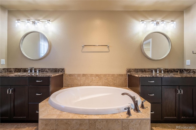 bathroom with tiled tub and vanity