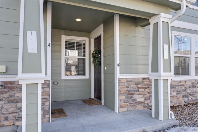 doorway to property with stone siding and a porch