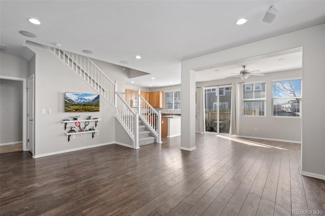 unfurnished living room with dark wood-type flooring, stairway, and baseboards