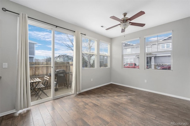 spare room with a ceiling fan, visible vents, baseboards, and wood finished floors