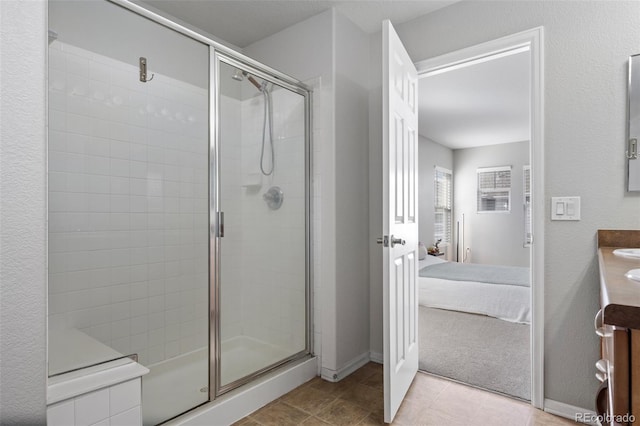 full bath featuring a stall shower, ensuite bath, vanity, and baseboards