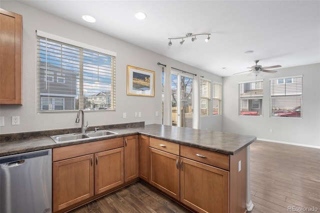 kitchen with a peninsula, a sink, dark wood-style floors, dishwasher, and dark countertops