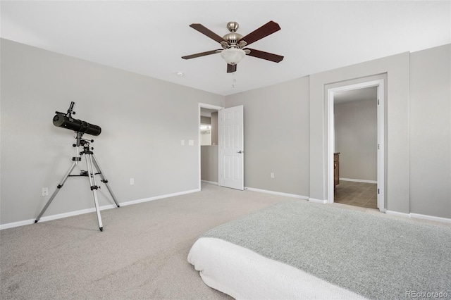 carpeted bedroom featuring ensuite bath, baseboards, and a ceiling fan